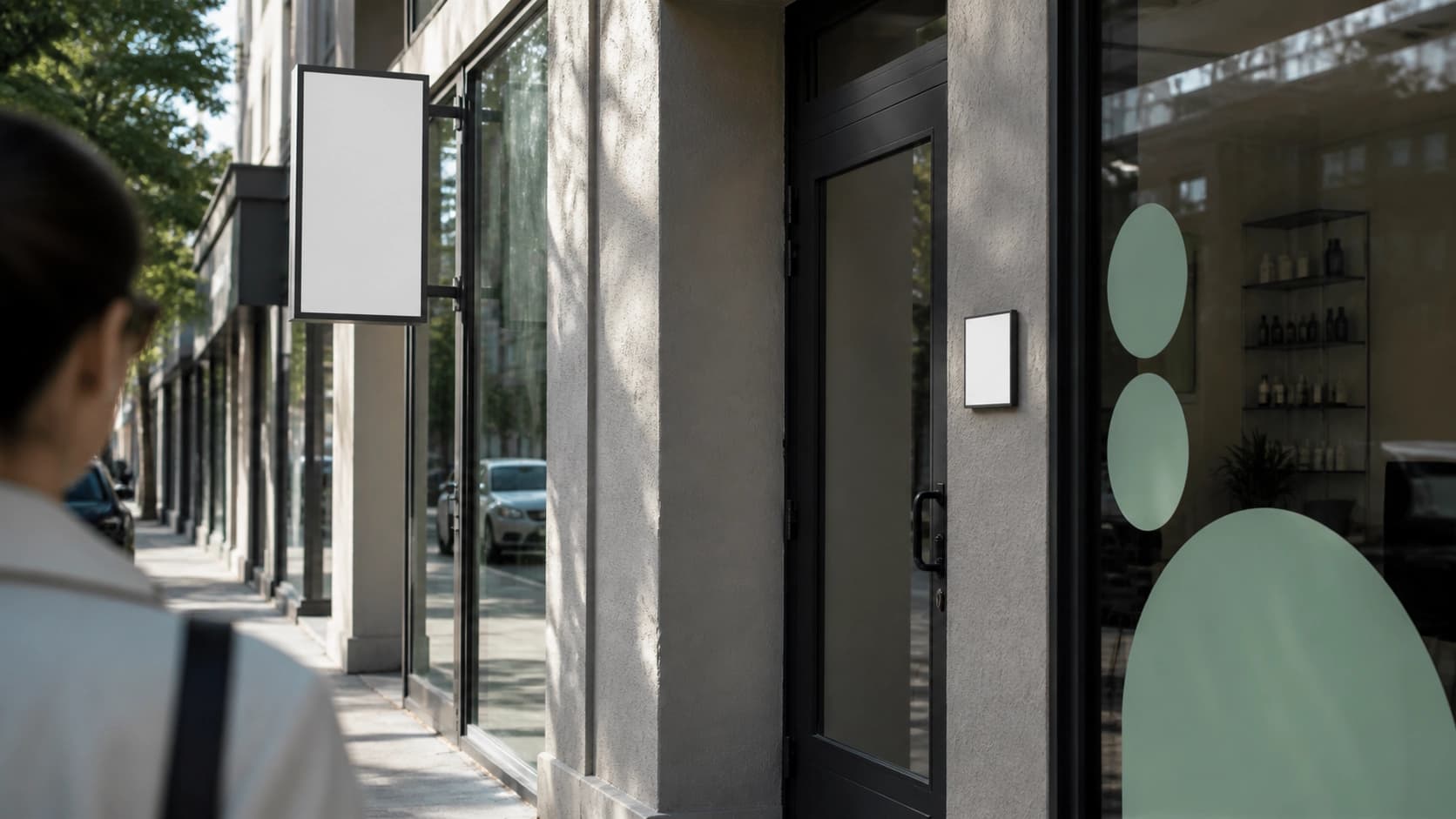A pedestrian approaches a storefront with blank blade, door, and window signage surfaces viewed from the sidewalk.
